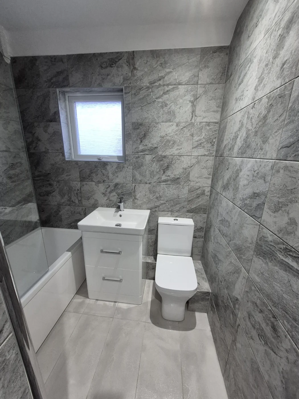 Bath, white vanity unit and toilet with grey wall finishes — Queenborough bathroom renovation